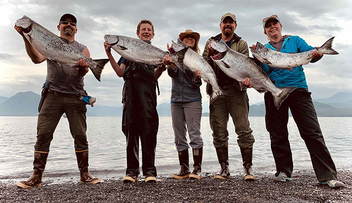 Group of people holding fresh-caught salmon